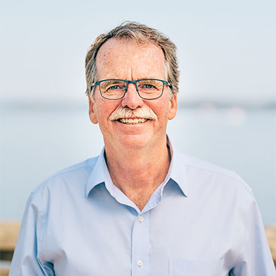 Rob Botterell - Candidate for Saanich North and the Islands Rob Botterell smiling in front of a calm waterfront background.